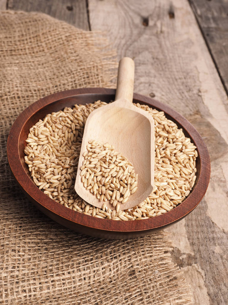 Organic peeled oats in a wooden bowl on a rustic wooden table - Fotoğraf, Görsel