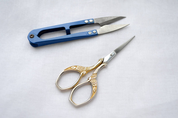 Beautiful graceful scissors with pattern for sewing, manicure scissors, scissors for seams, on white fabric - Photo, Image