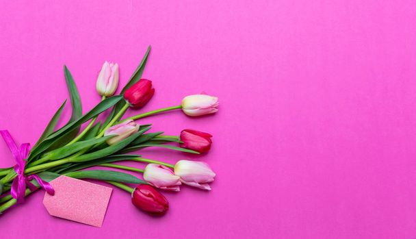 Матері, концепція жіночого дня. Тюльпани букет і порожня мітка на яскраво-рожевому фоні, вид зверху, місце для тексту
 - Фото, зображення