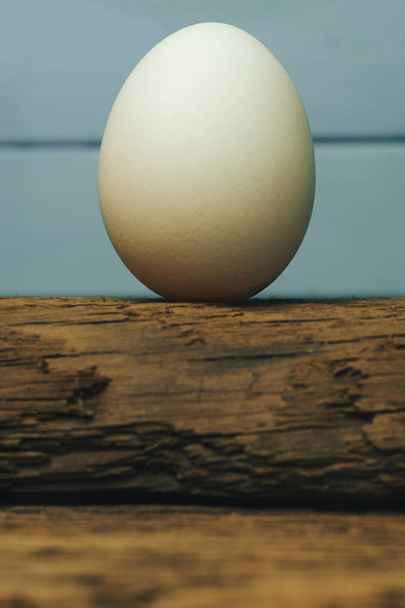 Eski meşe ahşap masa mavi zemin üzerine beyaz yumurta. - Fotoğraf, Görsel