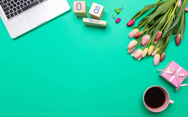 Concepto de día para mujer. Ramo de tulipanes rosados, fecha 8 de marzo y computadora portátil sobre fondo verde pastel, vista superior, espacio para copiar
 - Foto, imagen