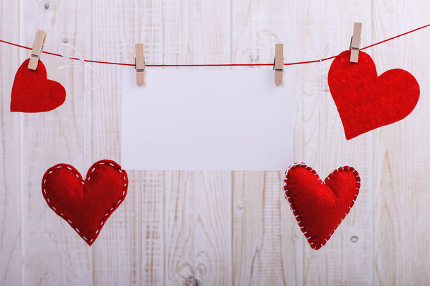 Handmade red felt hearts and white paper hanging on rope with clothespins. Concept, banner, copy space, form. - Zdjęcie, obraz