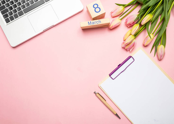 Frauentag-Konzept. rosa Tulpenstrauß, Datum 8. März und Computer-Laptop auf rosa Pastellhintergrund, Draufsicht, Kopierraum - Foto, Bild