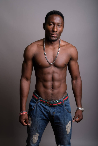 Young handsome African man shirtless against gray background - 写真・画像