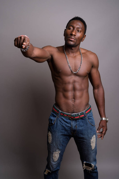Young handsome African man shirtless against gray background - Фото, зображення