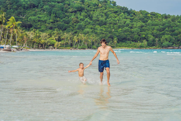 Dad plays with his son in the sea - Фото, изображение