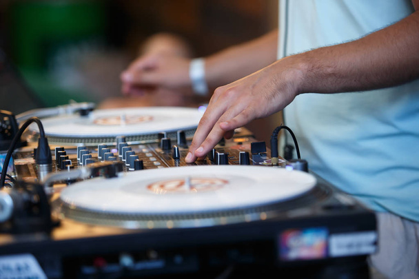 Hip hop party dj scratches vinyl records with music in night club.Professional disc jockey audio equipment on concert stage.Djs hands on record and sound mixer panel - Photo, Image