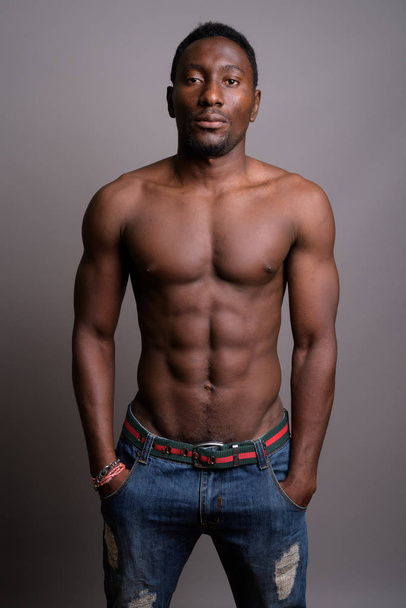 Молодой красивый африканский мужчина без рубашки на сером фоне
 - Фото, изображение
