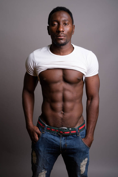 Молодой красивый африканский мужчина на сером фоне - Фото, изображение