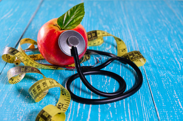 Zdravotní péče kontrolovat a hubnout pro zdraví. Svinovací metr pro tělo, apple a stetoskop na dřevěný stůl na klinice. Copyspace. - Fotografie, Obrázek