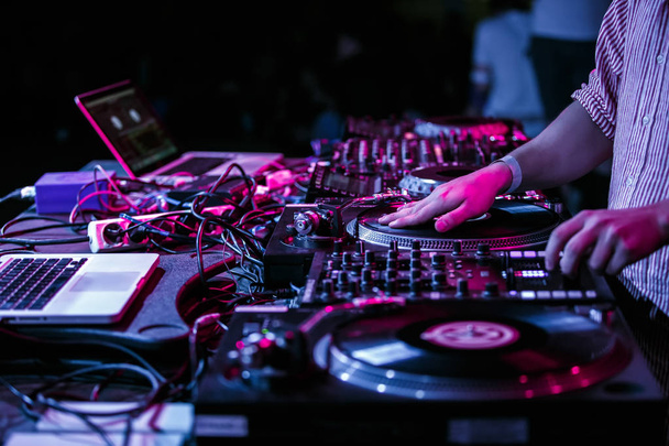 Club party dj plays music with turntables.Hands of hip hop disc jockey man scratching vinyl records on stage in nightclub.Professional audio equipment on scene.Retro turn table player and sound mixer - 写真・画像
