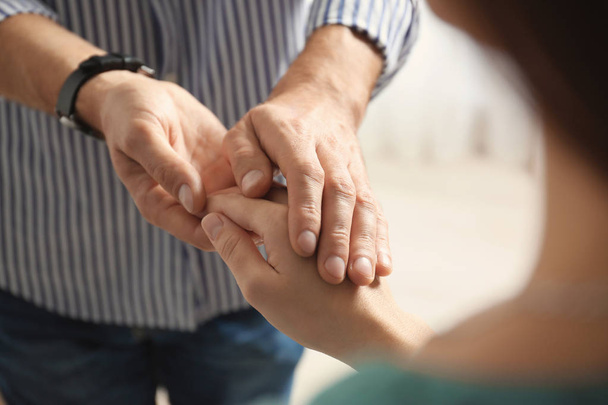 Man comforting woman on light background, closeup of hands. Help and support concept - Zdjęcie, obraz