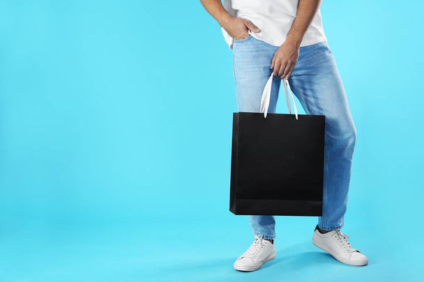 Young man holding paper bag on color background, closeup.  Mockup for design - Photo, Image