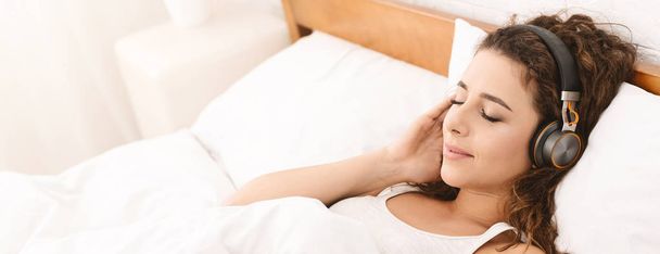 Mujer joven escuchando audio libro en la cama
 - Foto, imagen