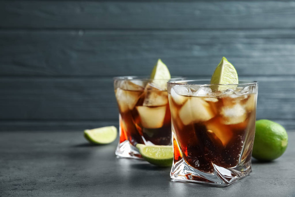 Glasses of cocktail with cola, ice and cut lime on table. Space for text - Fotografie, Obrázek