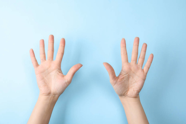 Woman showing sign ten on color background, closeup. Body language - Foto, afbeelding