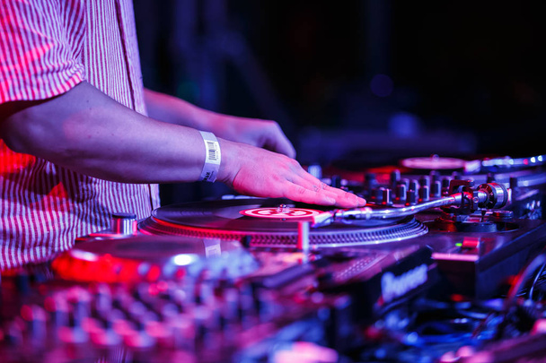 KIEV-11 AUGUST,2018: Hip hop Dj Fame scratches vinyl records on concert in night club.Professional disc jockey scratch and mix muscial tracks with retro Technics SL-1210 turn table player on party - Fotoğraf, Görsel