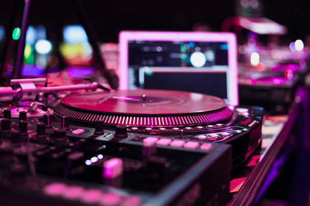 Professional dj tur ntable deck on stage in nightclub.Disc jockey cd player device on scene in red lights.Play and remix musical tracks on club party with modern digital turntables  - Foto, Bild