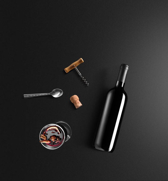 Mulled wine recipe ingredients and kitchen accessories, bottle of red wine, cinnamon, anise stars, orange, brown sugarand spice on black background. - Фото, изображение