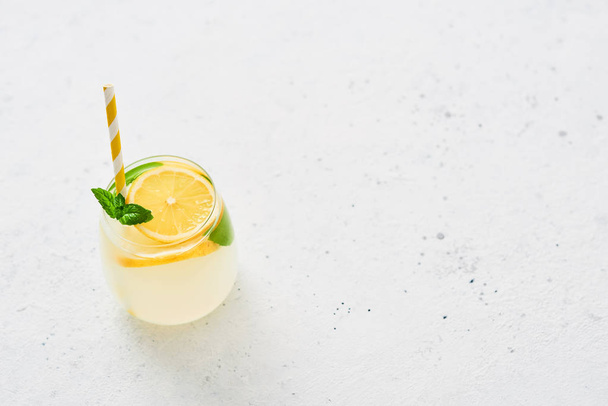 Ice cold summer drink. Traditional lemonade or mojito with lemon, mint and ice on white background. Copy space for text. Top view. - Foto, immagini