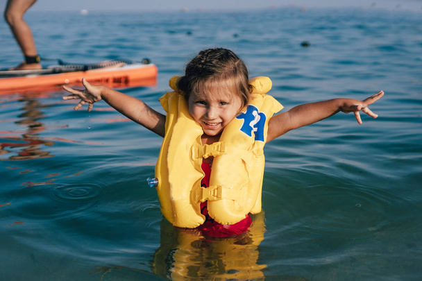 Little girl in a life jacket bathe in the sea. - Photo, Image