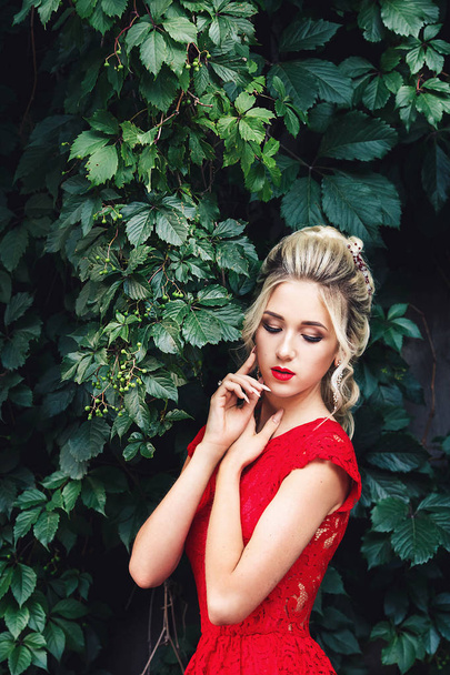 jolie jeune fille blonde en robe rouge posant près d'un vignoble sauvage
. - Photo, image