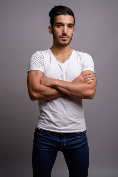 junger gutaussehender persischer Mann mit grauem Hintergrund - Foto, Bild