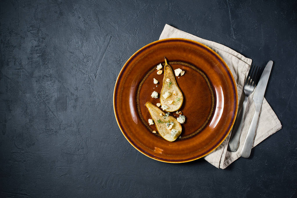 Ιταλική αχλάδι ψημένο με Γκοργκοντζόλα, καρύδια και σάλτσα μάνγκο, μαύρο φόντο - Φωτογραφία, εικόνα