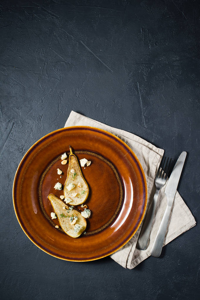 Pera al forno italiana con gorgonzola, noci e salsa di mango, fondo nero
 - Foto, immagini