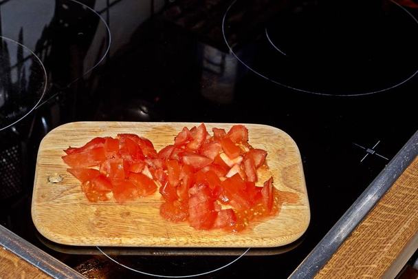 Chef tranchant la tomate, Solanum lycopersicum sur la planche à découper avec un couteau
. - Photo, image