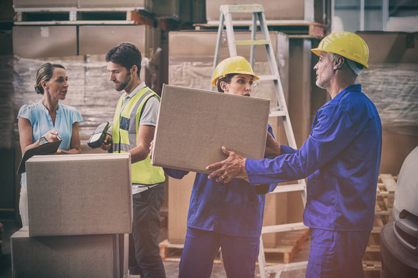Coworkers looking at each other in warehouse - Photo, image