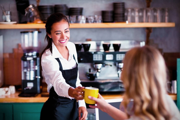 Waitress offering a cup of coffee in cafe - Foto, Bild