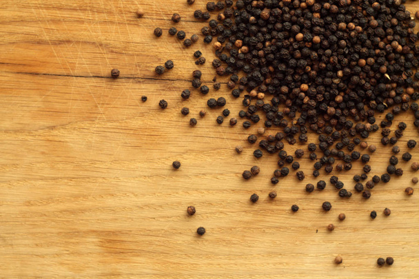 Black pepper close-up on wooden desk. Abstract background and texture for design. - Photo, Image