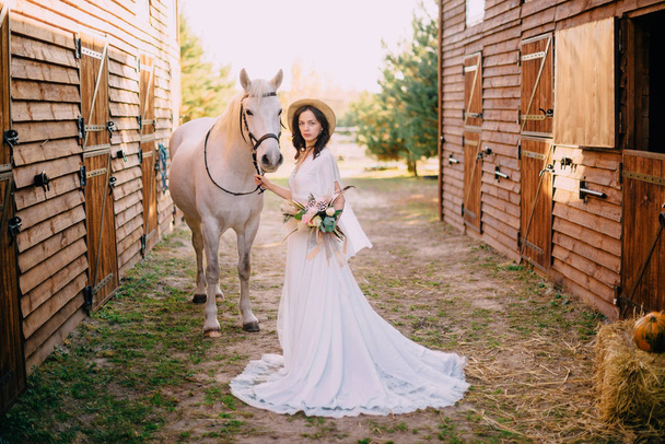 young boho style bride is stroking white horse - Фото, изображение