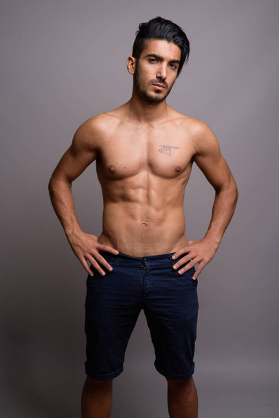 Young handsome Persian man shirtless against gray background - Photo, Image