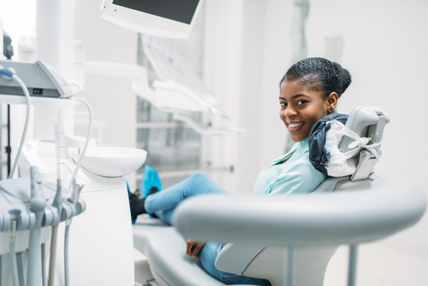 Patiente souriante sur chaise, visite à la clinique dentaire. Femme en dentisterie cabinet, stomatologie, soins dentaires
 - Photo, image