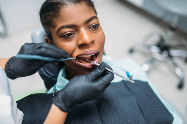 Zubní lékař zkoumá zuby pacientka v zubní klinice. Žena v zubním lékařství kabinet, stomatologie - Fotografie, Obrázek