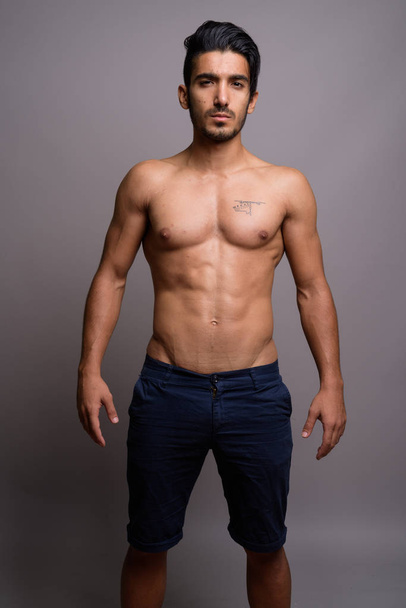 Young handsome Persian man shirtless against gray background - Fotó, kép