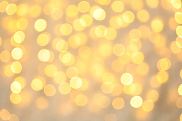 Blurred view of golden Christmas lights as background. Bokeh effect - 写真・画像