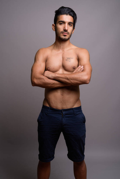 Young handsome Persian man shirtless against gray background - Fotoğraf, Görsel