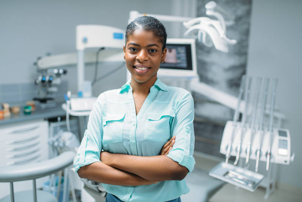 Patiente souriante en clinique dentaire, équipement médical en arrière-plan. Femme en dentisterie cabinet, stomatologie, soins dentaires
 - Photo, image
