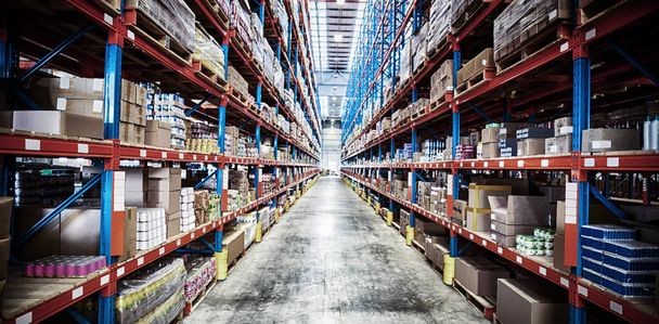 Products arranged on rack in illuminated warehouse - Photo, image