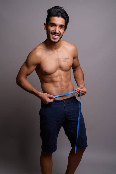 Young handsome Persian man shirtless against gray background - Fotoğraf, Görsel