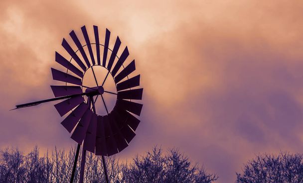 decoración vintage, un antiguo molino de viento oxidado clásico al atardecer, cielo colorido y nubes, fondo agrícola o occidental - Foto, Imagen