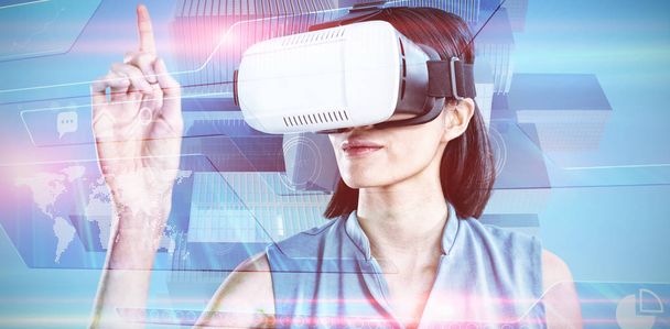 Female executive gesturing while using virtual reality headset against futuristic technology interface - Foto, afbeelding