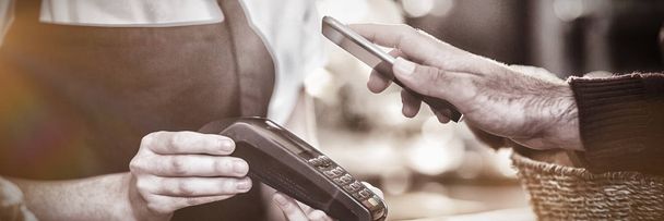 Customer paying bill through smartphone using NFC technology in cafe, Close-up - Fotoğraf, Görsel