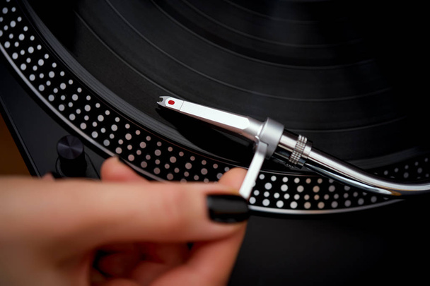 Closeup of turntable needle and blurred hand on background with black LP record - Photo, Image