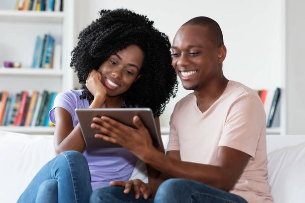African american couple watching movie with tablet computer indoors at home - Foto, Bild