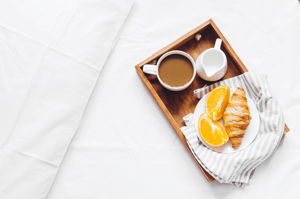 Romantyczne Walentynki śniadanie w łóżku, taca z rogalikami, filiżankę kawy espresso z mlekiem i świeżych pomarańczy. Dzień dobry pomysł. Ciesz się życiem powolny. Widok z góry. Miejsce. - Zdjęcie, obraz