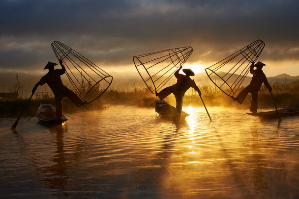 Siluety tří rybářů výkon na Inle lake Myanmar při východu slunce - Fotografie, Obrázek